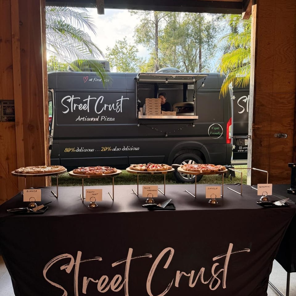 Street Crust artisanal pizza food truck with a variety of pizzas displayed on a branded table.